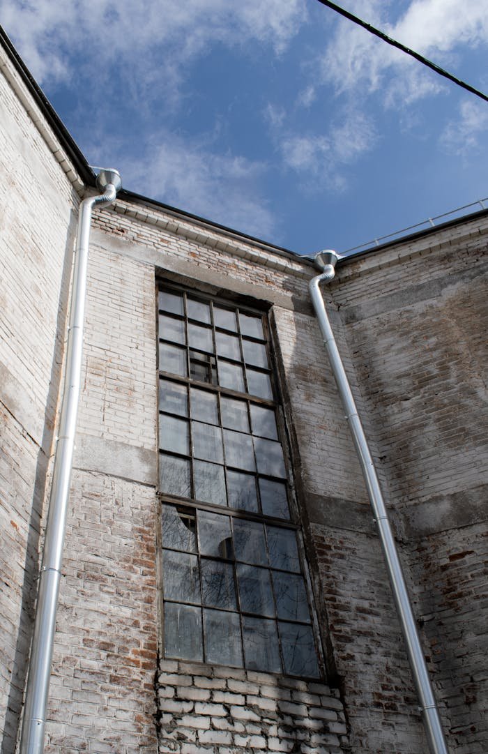 A tall abandoned brick building with broken glass windows and a clear blue sky.